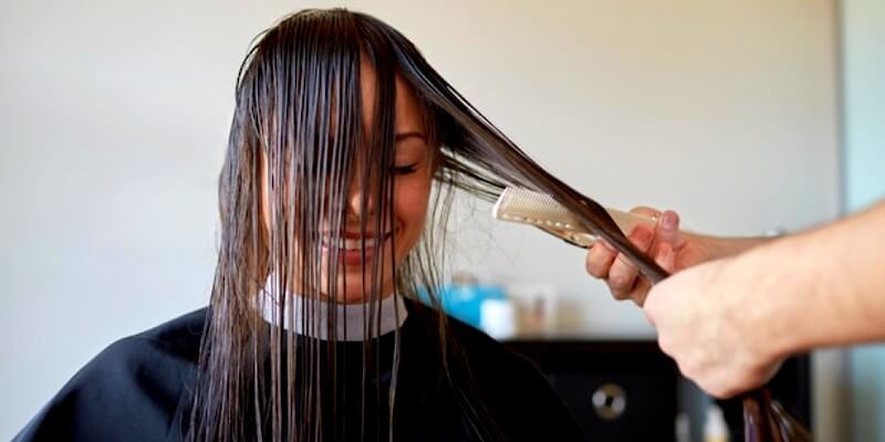 Jeune femme réalisant un lissage de cheveux dans un salon de coiffure
